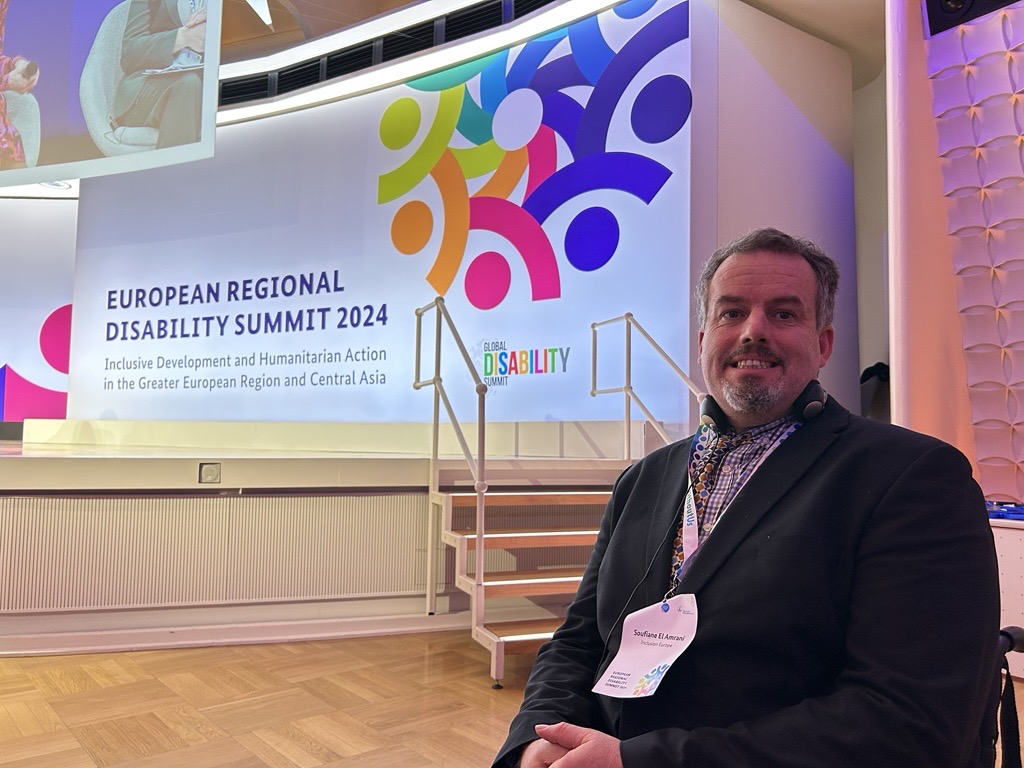 Soufiane El Amrani at the European Regional Disability Summit, with the event poster in background