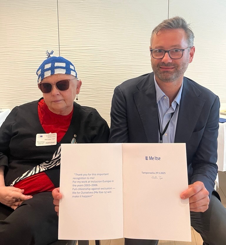 Ulla Topi and Milan Sverepa, holding a dedication from Ulla: "Thank you for this important recognition for me! For my work at Inclusion Europe. Full citizenship against exclusion. We for ourselves will make it happen."